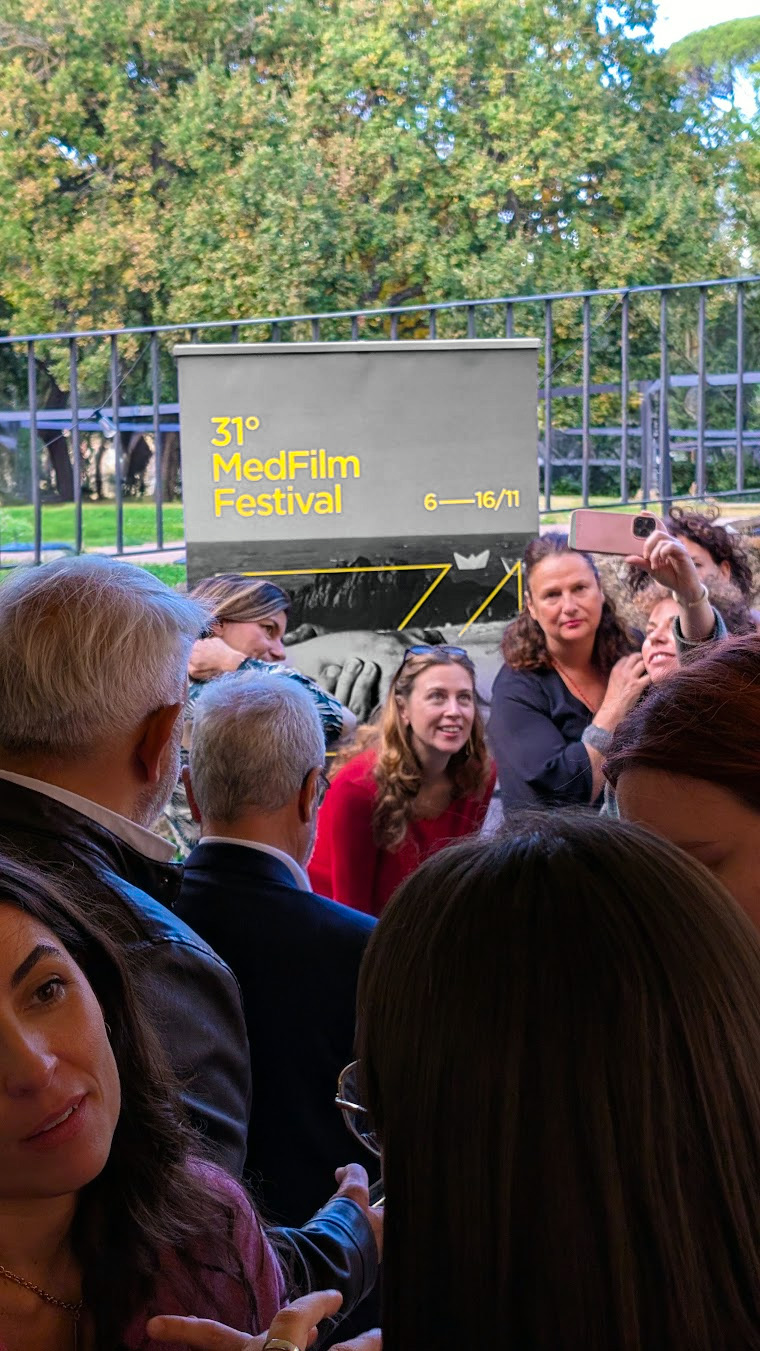 People taking a photo in front of the festival poster