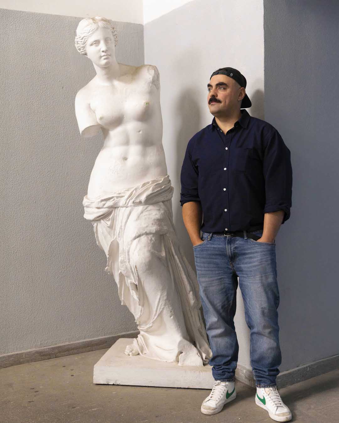 Gianluca Abbate posing in front of a copy of the Venus de Milo inside Brera Art High School